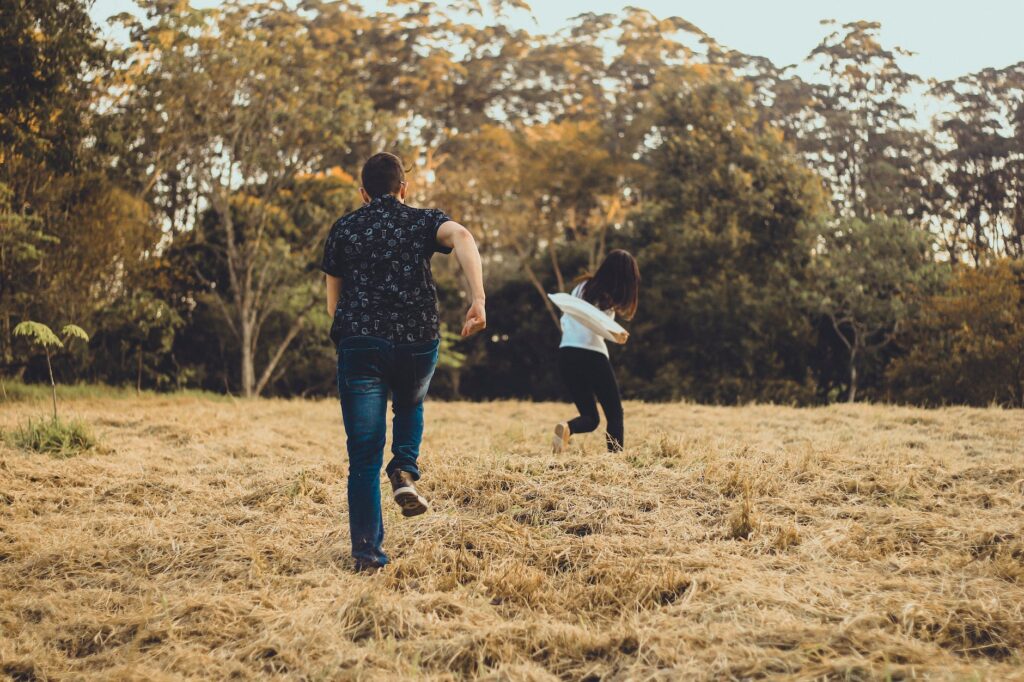 unrecognizable couple running on meadow in park