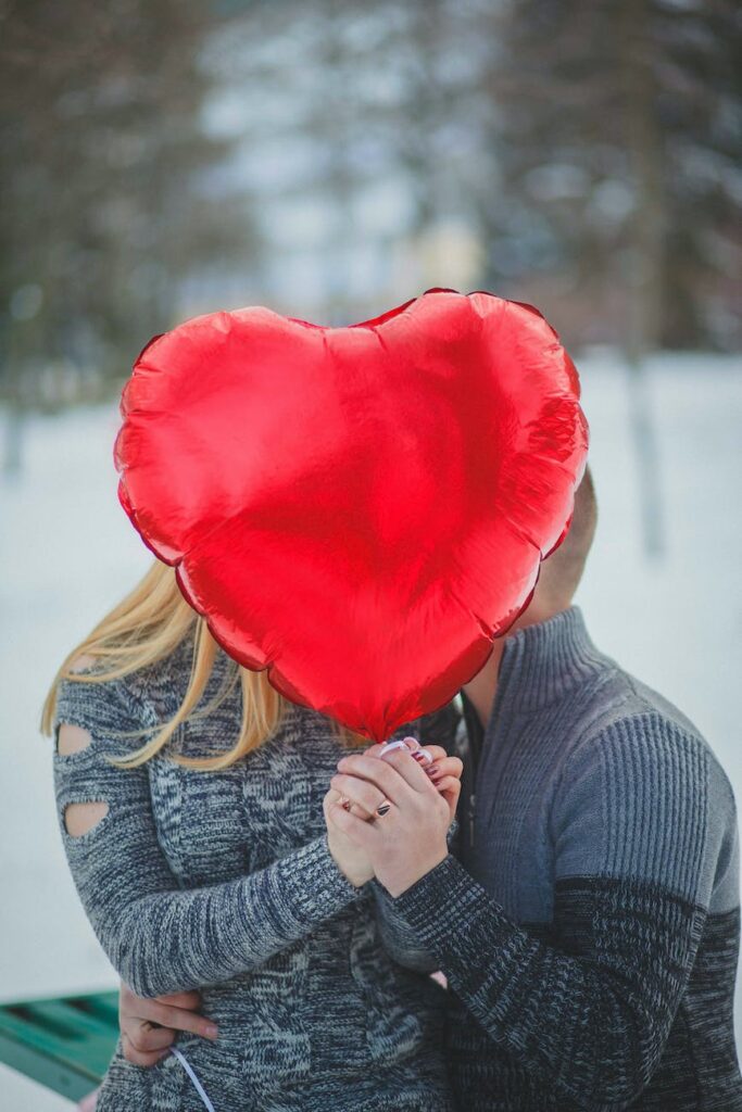 couple holding hands with red heart balloon